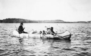 Black and white historical photograph of five Ojibwa Indians in a canoe, 1913.